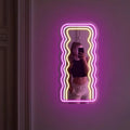 Wavy Neon Mirror illuminated in a dimly lit room for a cozy atmosphere.
